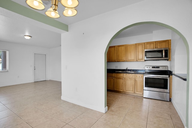 kitchen with sink, appliances with stainless steel finishes, light tile flooring, and an inviting chandelier