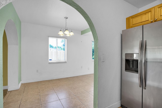 kitchen with hanging light fixtures, stainless steel fridge, a notable chandelier, and light tile flooring