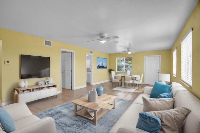 tiled living room with ceiling fan and a textured ceiling