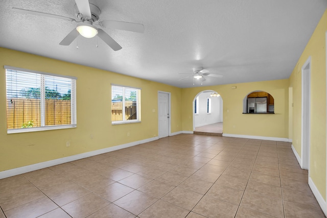 tiled empty room featuring a textured ceiling and ceiling fan