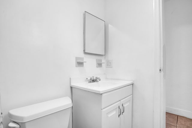 bathroom featuring toilet, tile flooring, and vanity