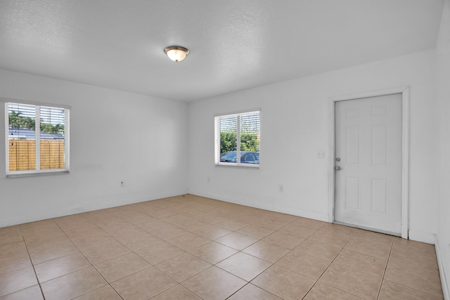 spare room featuring a wealth of natural light and light tile flooring