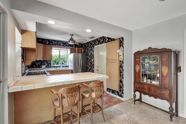 kitchen with light carpet, backsplash, ceiling fan, and stainless steel refrigerator