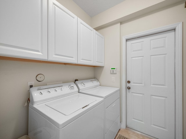 laundry area featuring light tile floors, cabinets, and washer and dryer