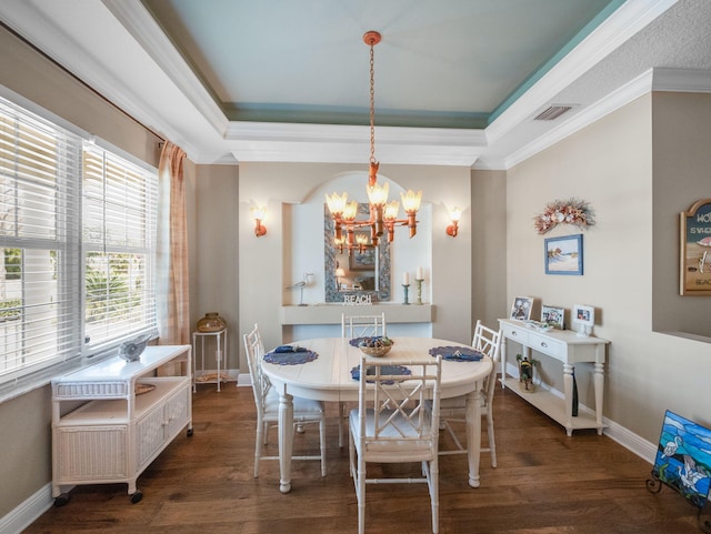 dining area with a raised ceiling, dark hardwood / wood-style flooring, ornamental molding, and a chandelier