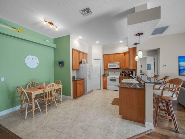 kitchen featuring a textured ceiling, pendant lighting, white appliances, and kitchen peninsula