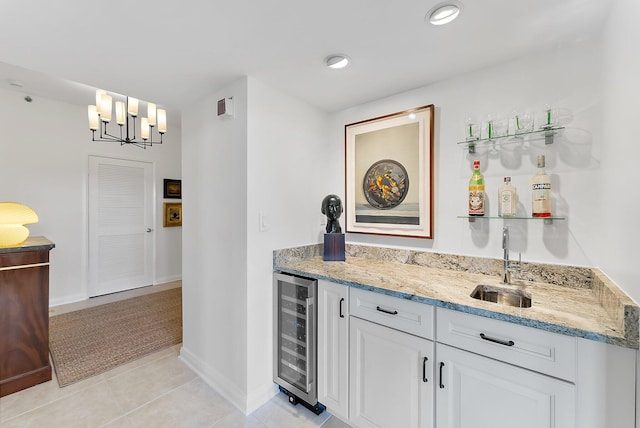 bar featuring decorative light fixtures, white cabinetry, sink, beverage cooler, and light stone counters