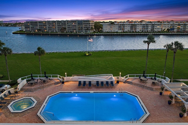 pool at dusk with a patio, a water view, and a community hot tub