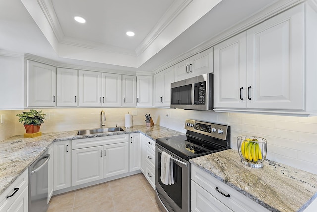 kitchen with sink, stainless steel appliances, ornamental molding, white cabinets, and a raised ceiling