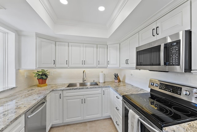 kitchen with appliances with stainless steel finishes, a tray ceiling, sink, and white cabinets