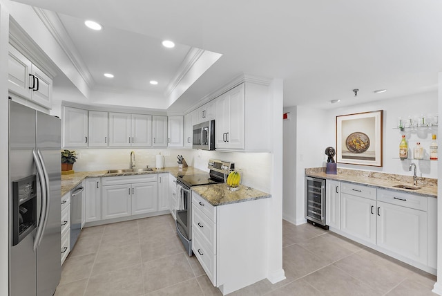 kitchen with a raised ceiling, white cabinetry, sink, beverage cooler, and stainless steel appliances