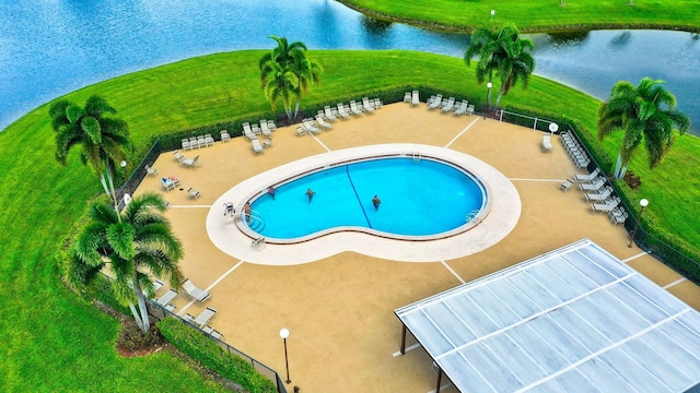 view of pool featuring a lawn, a water view, and a patio area