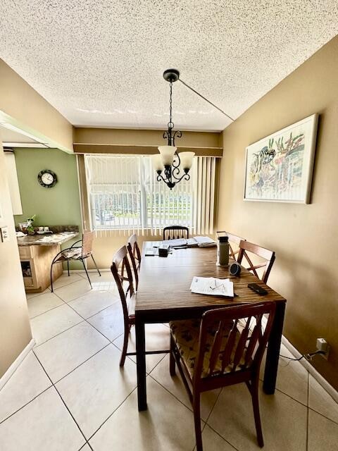 tiled dining space featuring an inviting chandelier and a textured ceiling