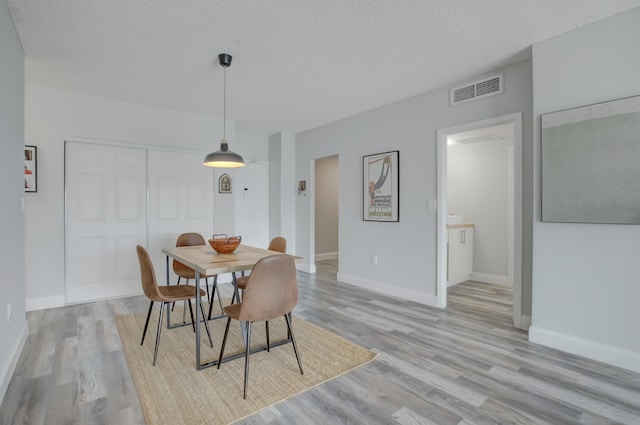 dining space with a textured ceiling and light hardwood / wood-style floors