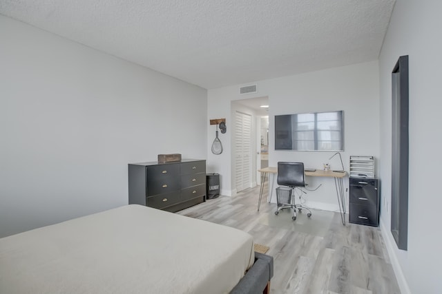 bedroom with a textured ceiling and light wood-type flooring