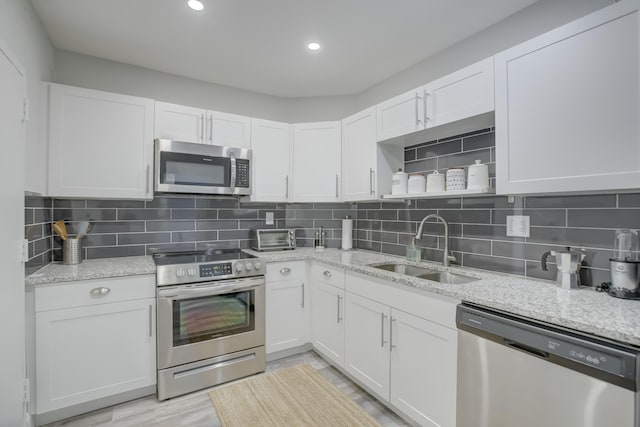 kitchen featuring appliances with stainless steel finishes, white cabinetry, backsplash, and sink