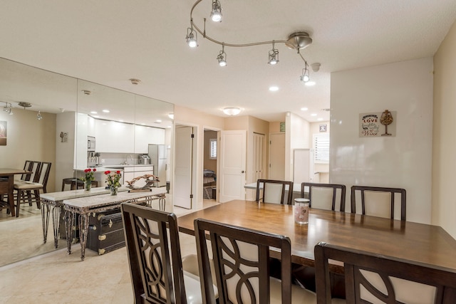 dining space with rail lighting and light tile floors