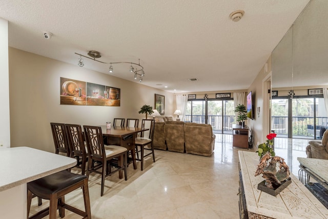 dining space with rail lighting, a textured ceiling, and light tile floors