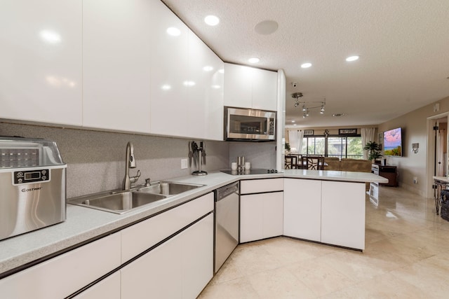 kitchen with kitchen peninsula, appliances with stainless steel finishes, sink, white cabinets, and a textured ceiling