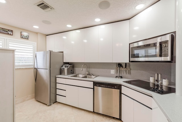 kitchen with white cabinetry, light tile flooring, sink, stainless steel appliances, and a textured ceiling