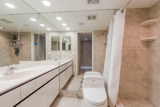 bathroom with tile walls, toilet, tile floors, and vanity with extensive cabinet space