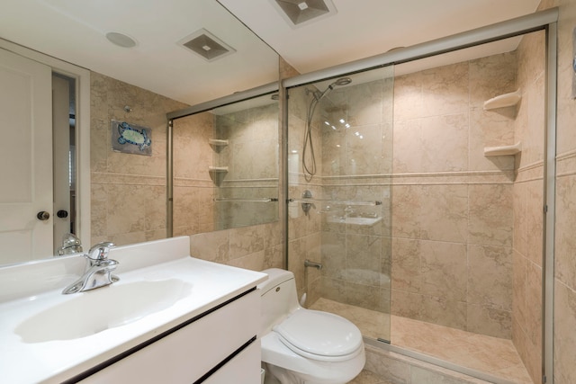 bathroom with tile walls, walk in shower, toilet, and large vanity