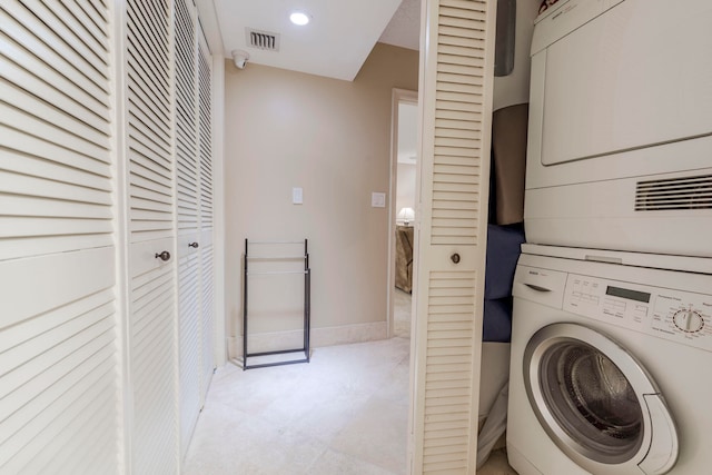 laundry area with light tile flooring and stacked washer and dryer