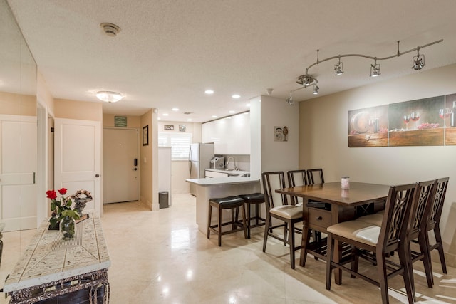 tiled dining space featuring a textured ceiling and sink