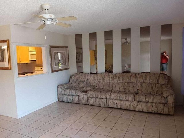 living room with a textured ceiling, light tile flooring, and ceiling fan