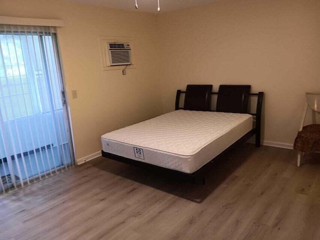 bedroom with hardwood / wood-style floors and a wall mounted air conditioner