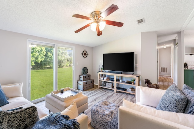 living room with a textured ceiling, ceiling fan, and light hardwood / wood-style flooring