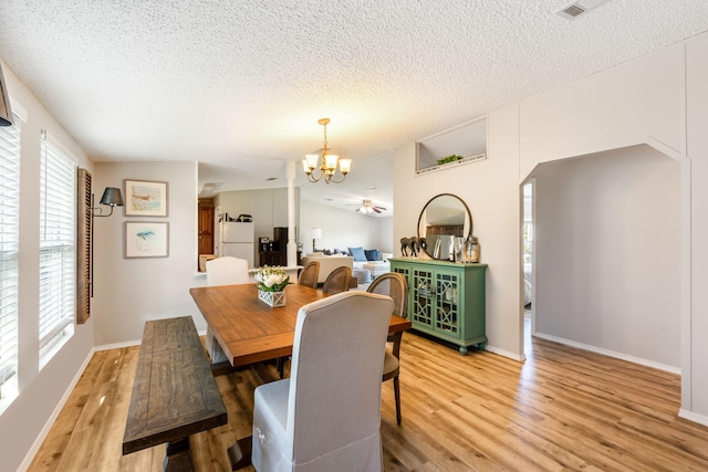 dining area featuring a notable chandelier, a textured ceiling, light hardwood / wood-style floors, and a healthy amount of sunlight