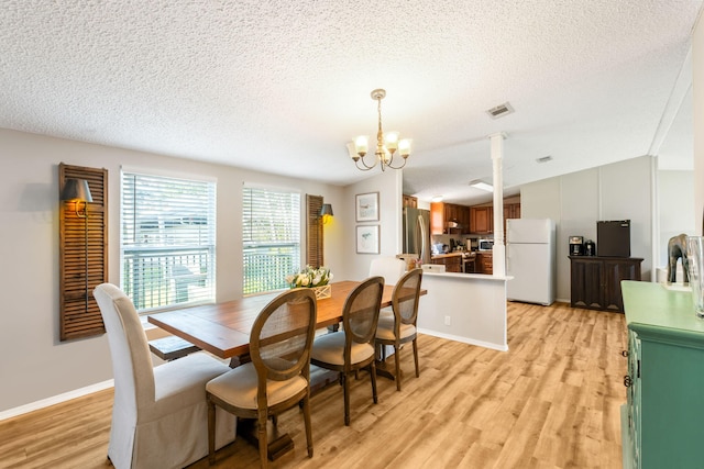 dining room featuring light hardwood / wood-style floors, a textured ceiling, and a chandelier