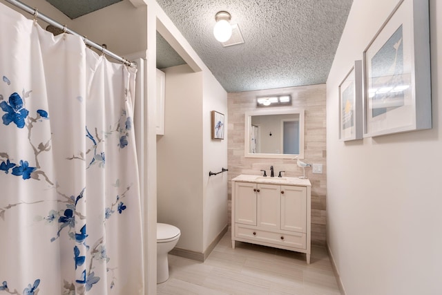 bathroom featuring tile walls, toilet, tile flooring, a textured ceiling, and large vanity