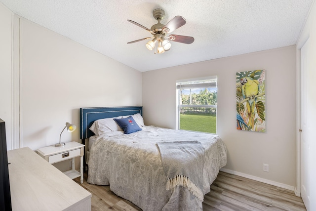 bedroom with a textured ceiling, light hardwood / wood-style floors, and ceiling fan