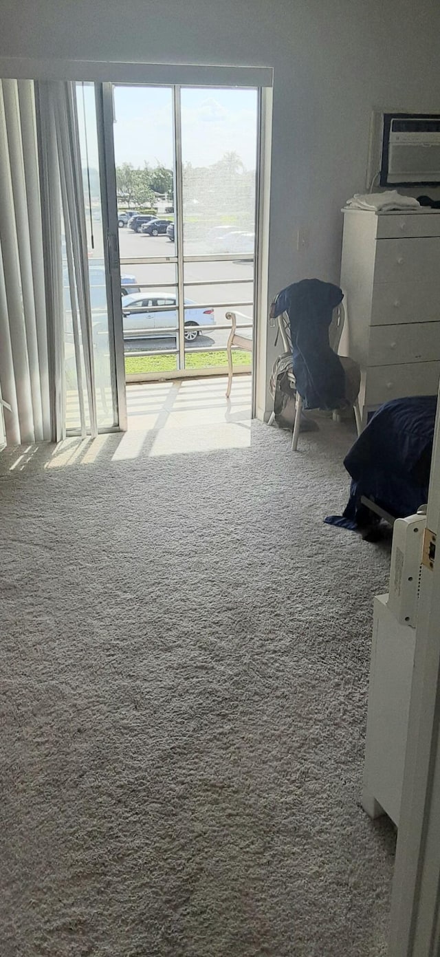 interior space featuring carpet, a wall mounted air conditioner, and a healthy amount of sunlight