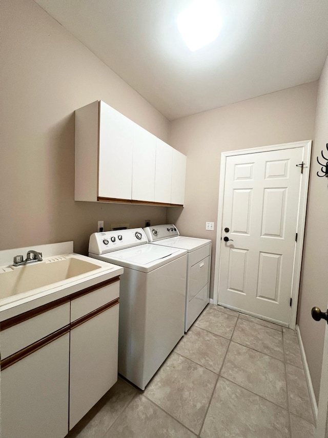 laundry area featuring light tile flooring, sink, cabinets, and washer and clothes dryer