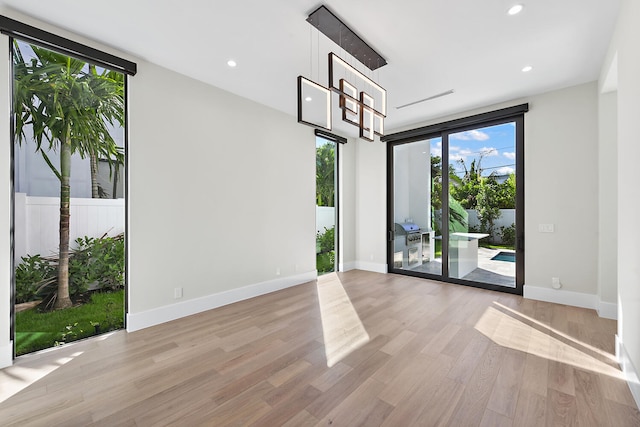 unfurnished room with a wall of windows and light hardwood / wood-style flooring