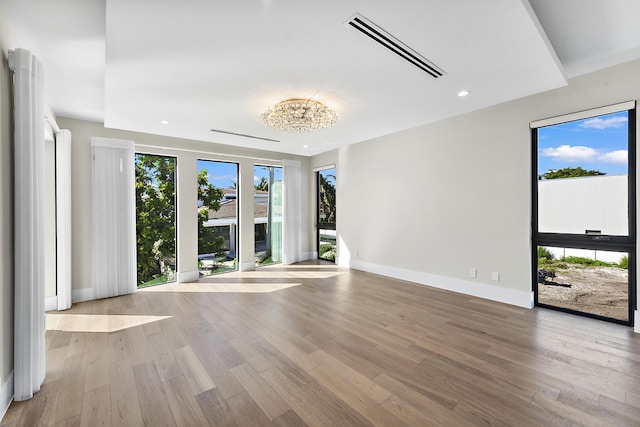 spare room featuring light hardwood / wood-style floors and a notable chandelier