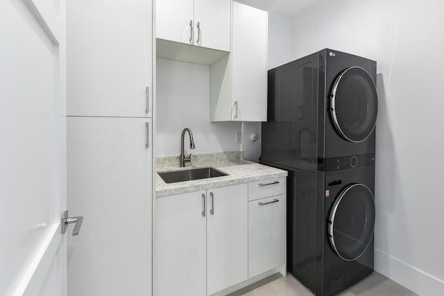 laundry room featuring cabinets, stacked washer and clothes dryer, and sink