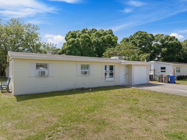 ranch-style house with a front yard, cooling unit, and a garage