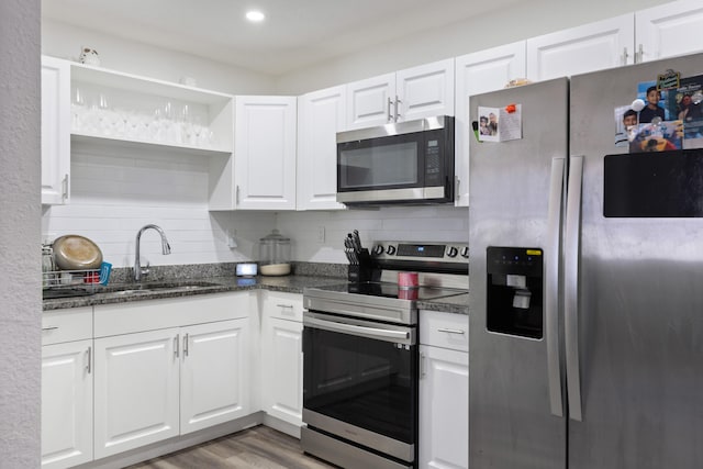 kitchen with appliances with stainless steel finishes, sink, backsplash, white cabinets, and dark hardwood / wood-style floors