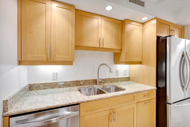 kitchen featuring light brown cabinetry, appliances with stainless steel finishes, sink, and light stone counters