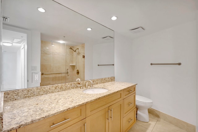 bathroom with tiled shower, toilet, vanity with extensive cabinet space, and tile flooring