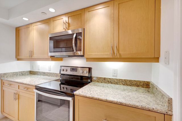 kitchen featuring light brown cabinets, stainless steel appliances, and light stone countertops