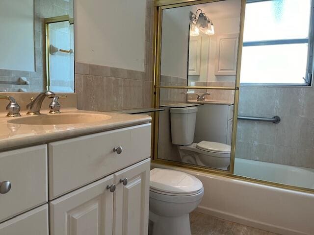 full bathroom with enclosed tub / shower combo, toilet, large vanity, and tile flooring