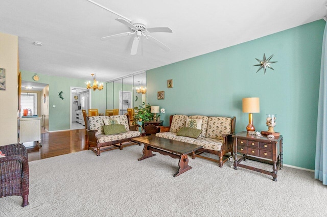 living room with ceiling fan with notable chandelier and light hardwood / wood-style flooring