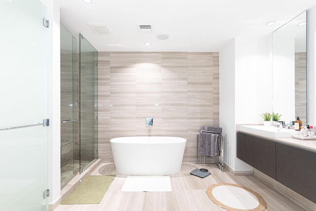 full bathroom with a freestanding tub, tile walls, a stall shower, vanity, and recessed lighting