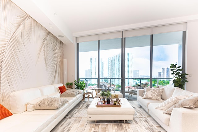 living area with a wall of windows, a view of skyline, and wood finished floors