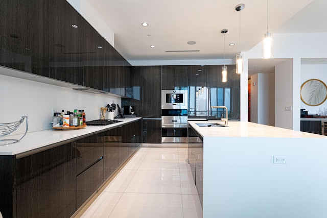 kitchen featuring modern cabinets, a sink, light countertops, hanging light fixtures, and a spacious island
